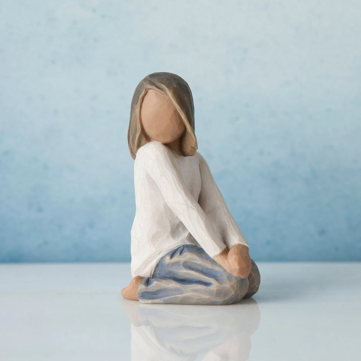 Little girl faceless figurine kneeling turning her head to the side - wearing white shirt and blue jeans