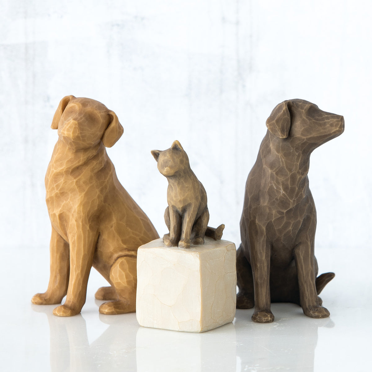 Set of two golden and grey dog figurines sitting in between grey cat figurine