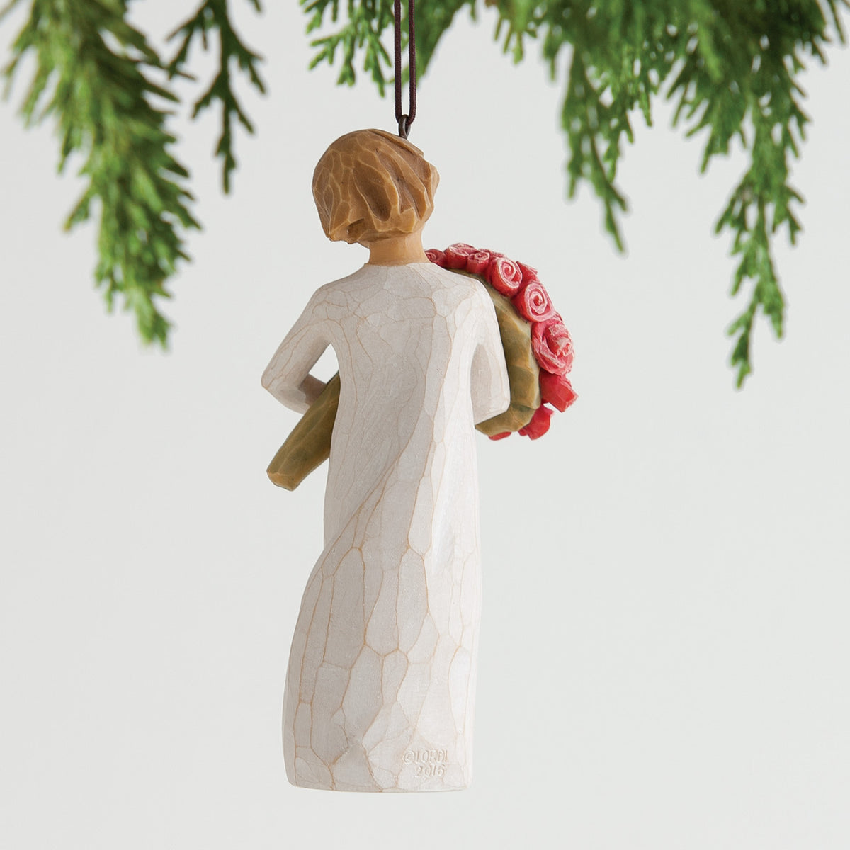 Back view of brunette woman figurine wearing white dress holding pink flowers hanging from tree
