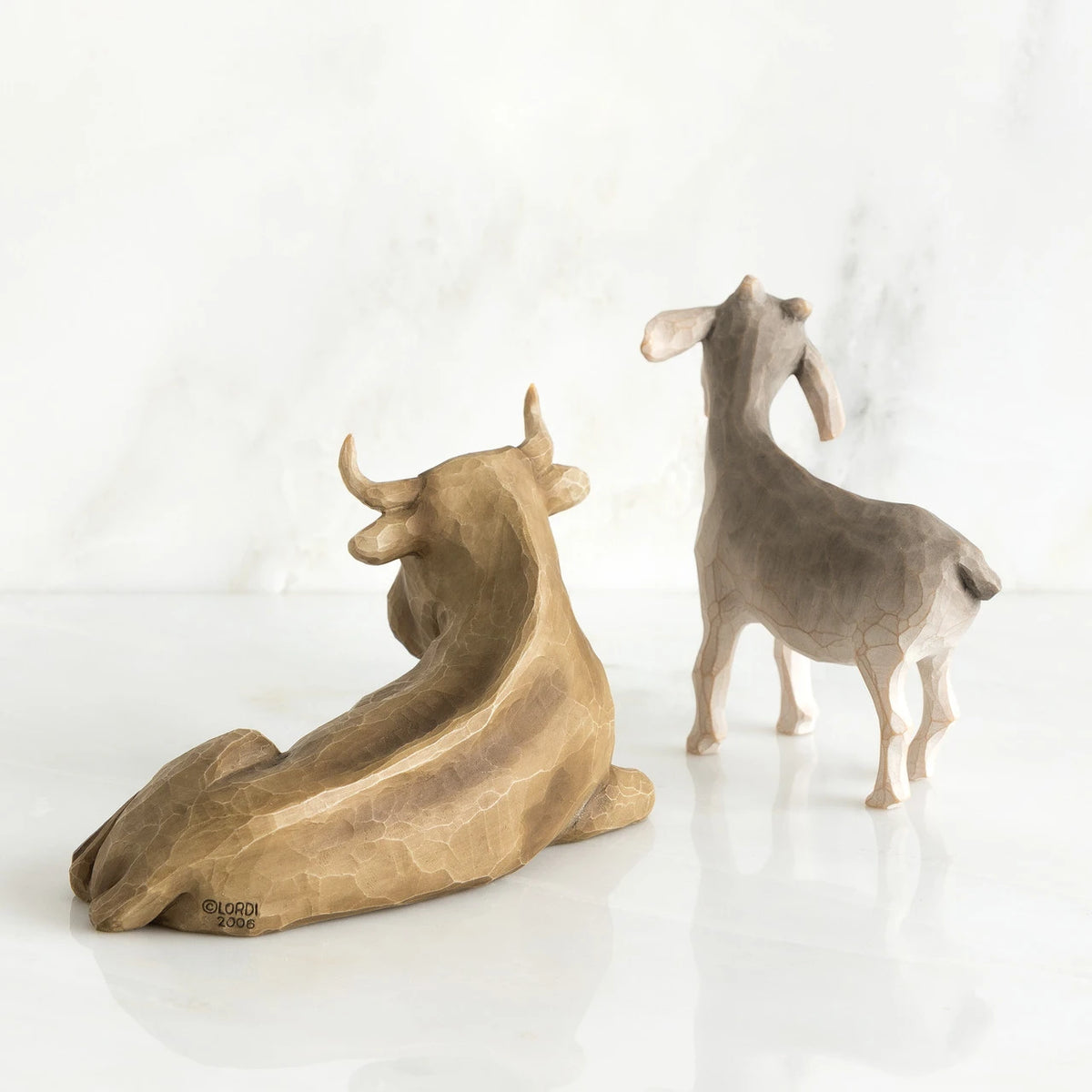 Back view of golden cow figurine and grey goat figurine