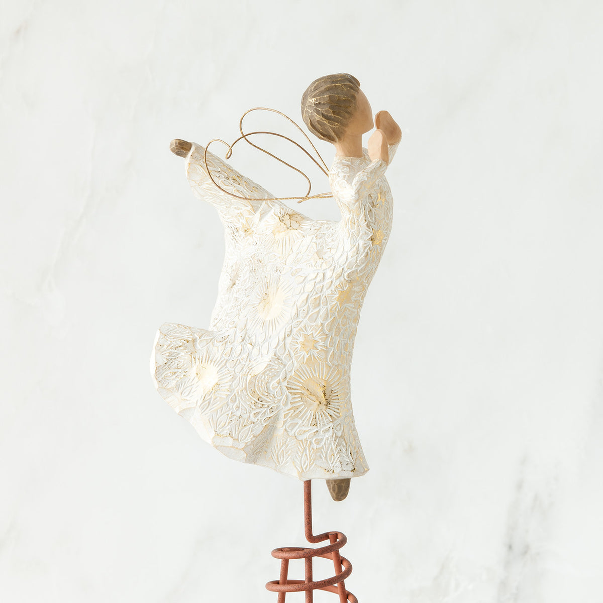 Side view of brunette angel figurine in white dress daning on red stand with arms to her face