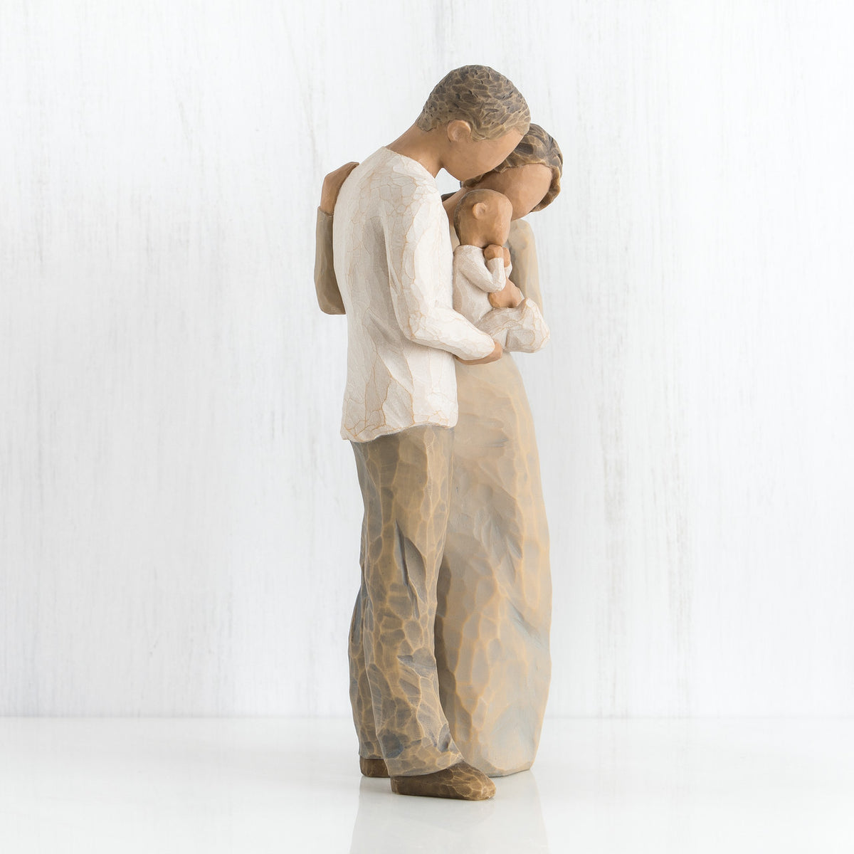 Side view of mother and father figurines holding a baby in their arms