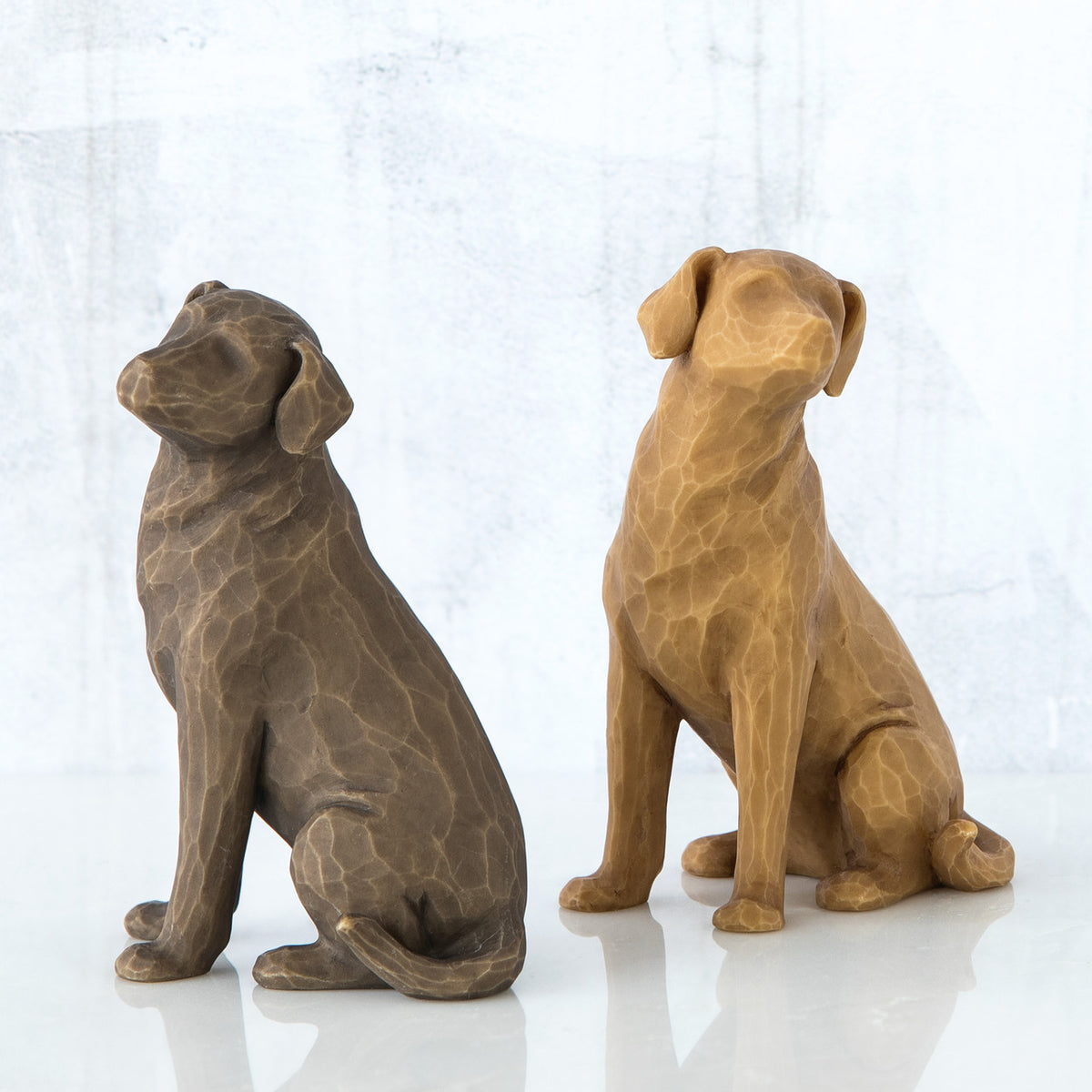 Set of two dog figurines sitting -one is brown and one is golden