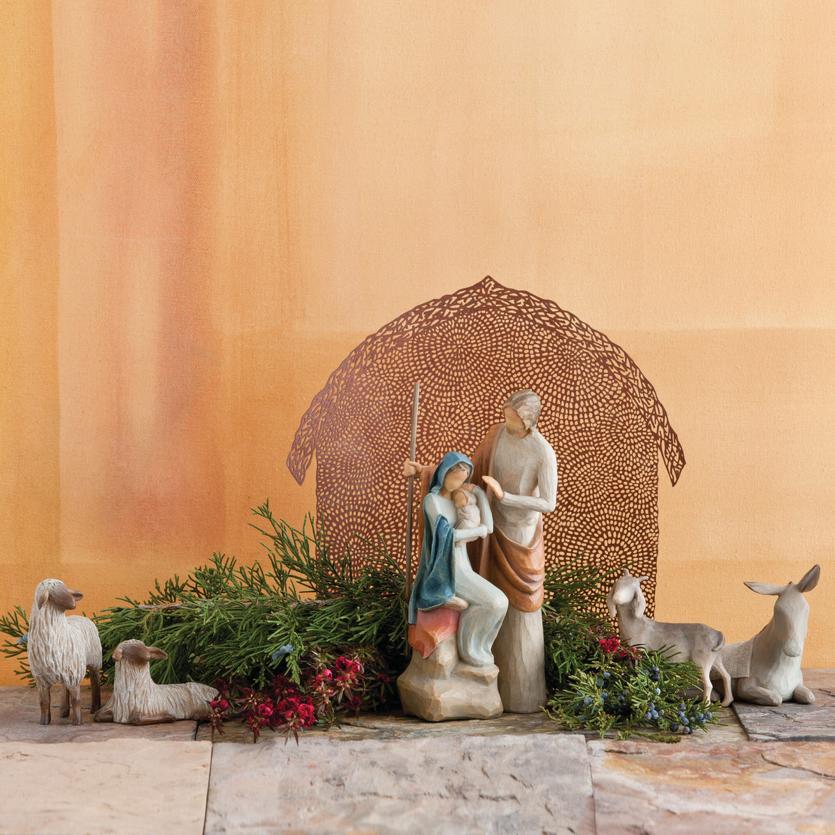 Far view of nativity scene figurines sitting on rock with brown barn in the background