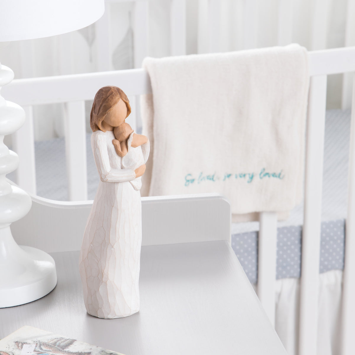 Front view of brunette woman figurine in white dress holding baby on white table