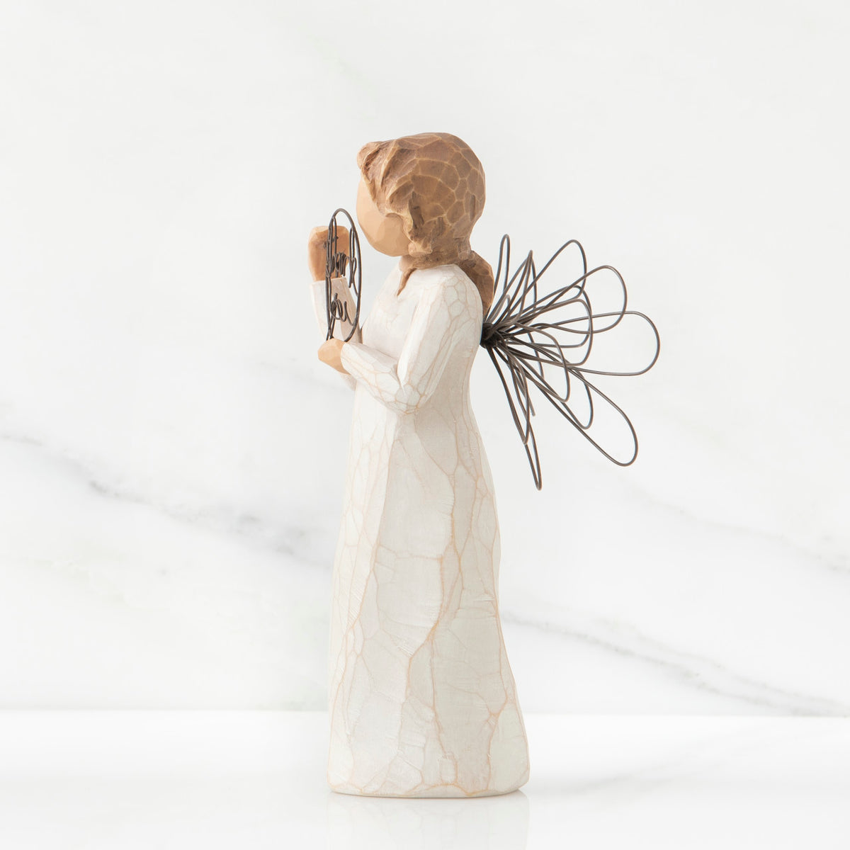 Right side view of angel with tied back brown hair, holding up a circular wire sign that says "thank you"