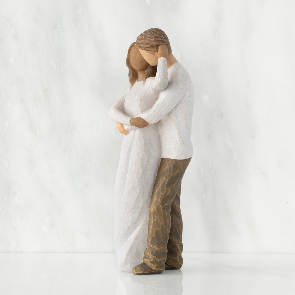 Left view of couple, standing with arms around each other. Woman has darker skin and hair; man has lighter skin and hair.