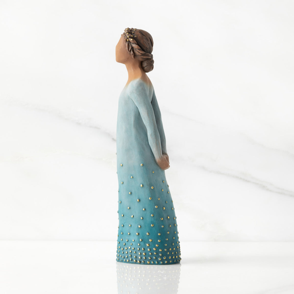 Left profile: Darker-skin figure, arms clasped behind back, hair and deep blue ombré garment dotted with gold leaf