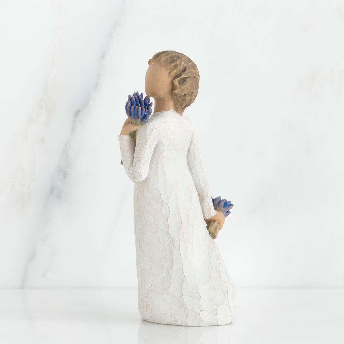 Brunette girl figurine in white dress holding blue flowers