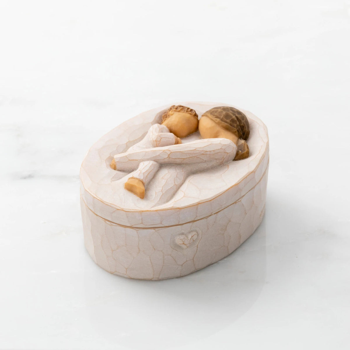 Willow Tree Tenderness Keepsake Box, 3.4" oval x 2.4" W x 1.5" D hand-painted resin box with removable lid off to one side, Lid has bas-relief carving of woman holding toddler, touching foreheads, inside of box has sentiment