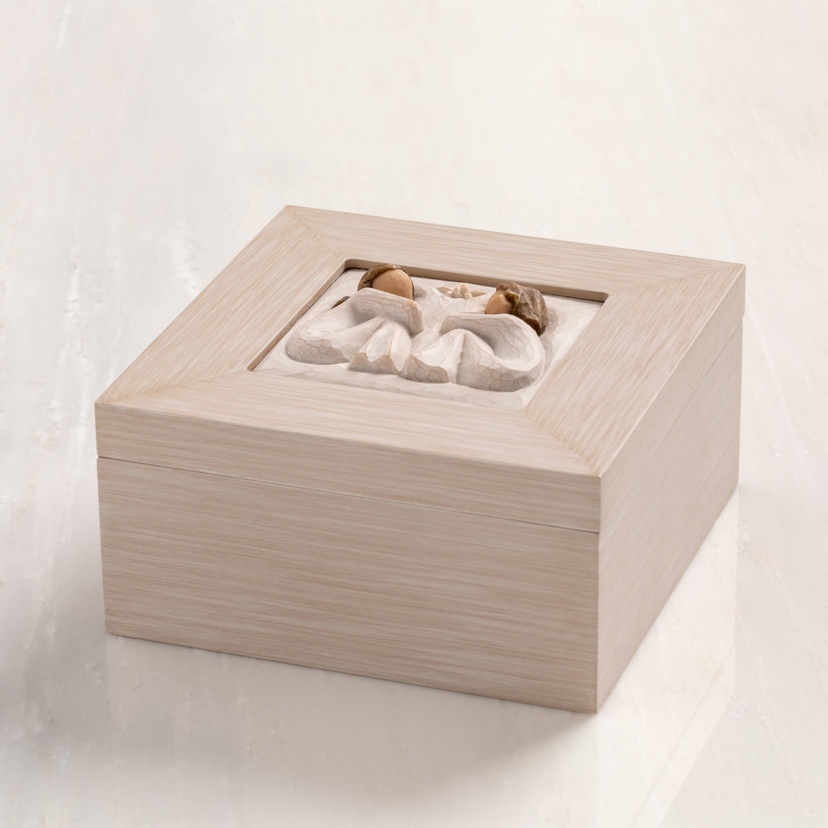 Side View: Cream wood box with hinged lid. Inset bas-relief plaque of two seated girls, facing each other.