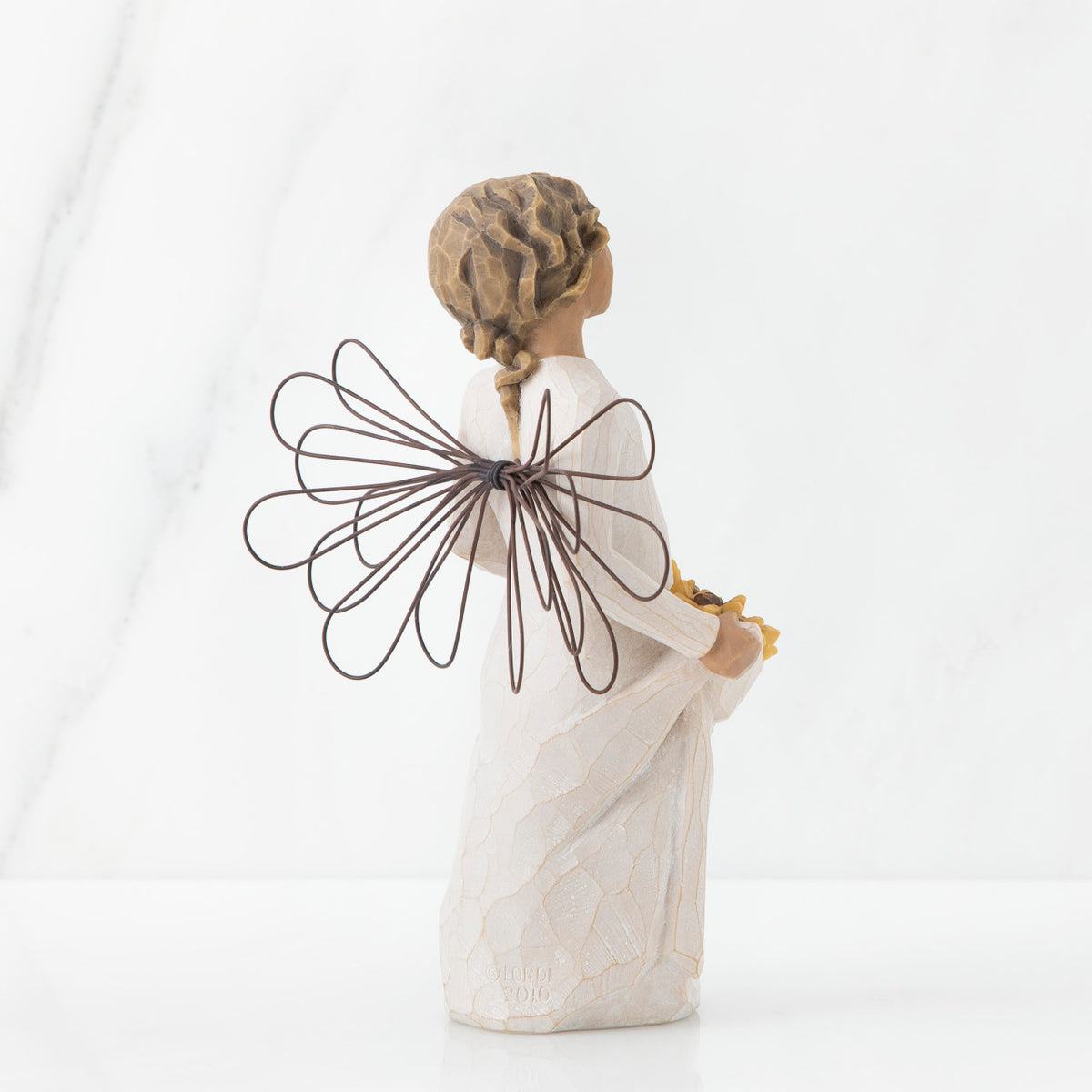 Back view of angel with tied back, curly, dark brown hair holding up a portion of her dress's skirt as it is full of sunflowers