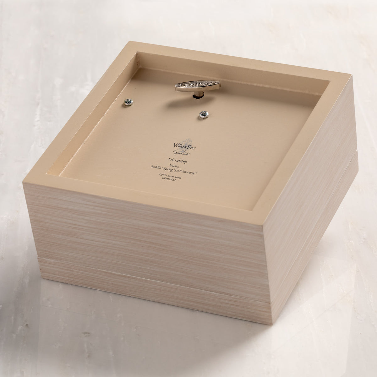 Bottom of cream wood box with hinged lid, showing winding mechanism for music.