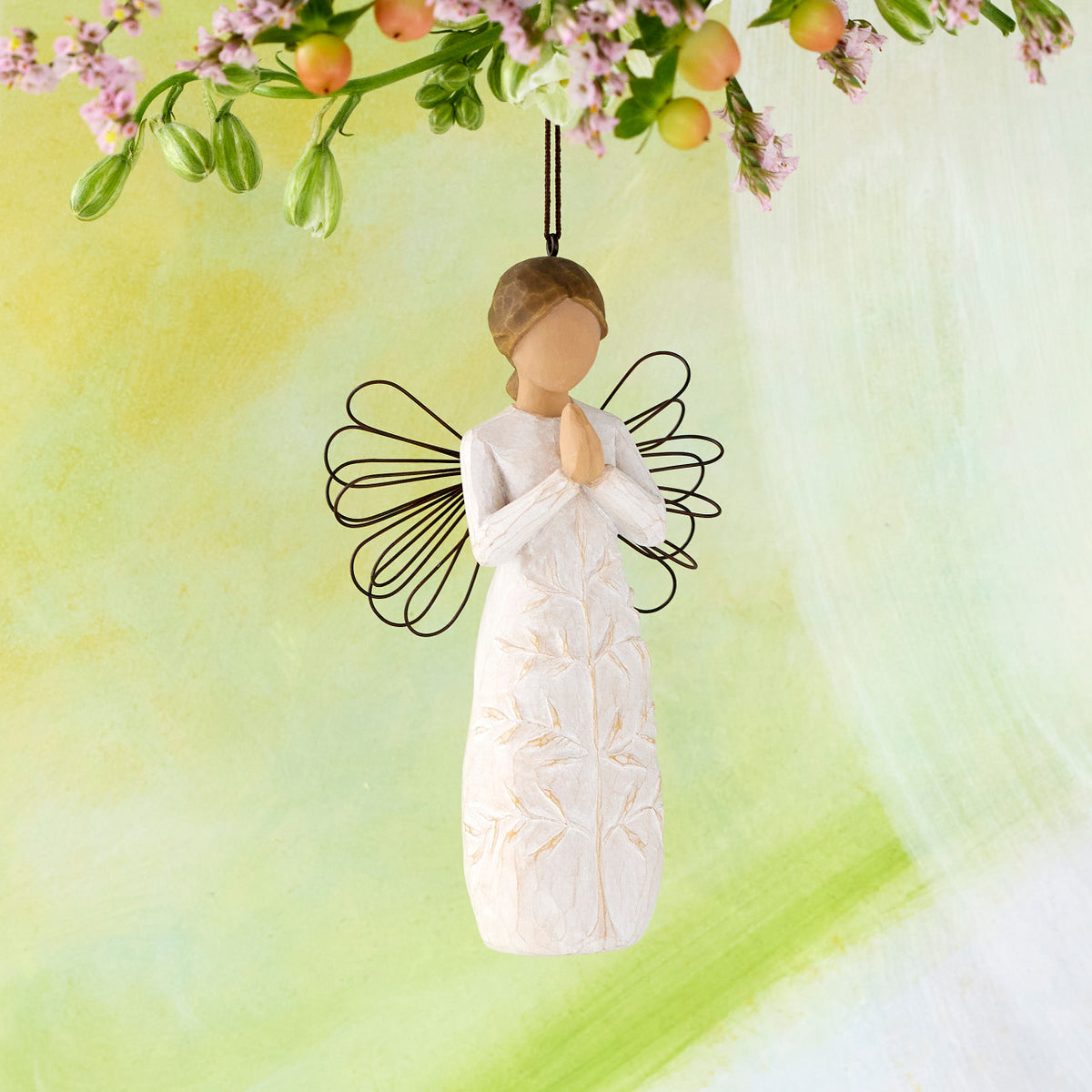Willow Tree a tree, a prayer Ornament, 4”h hand-painted resin angel figure in cream dress with wire wings, hands in prayer position, tree carving on dress, brown elastic cord, hanging in front of lime painting