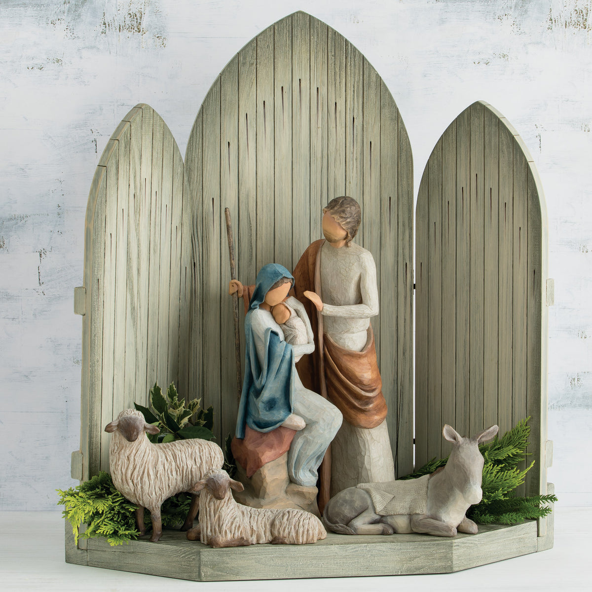 Grey barn figurine with nativity scene figurines sitting down with two white lamb figurines around them