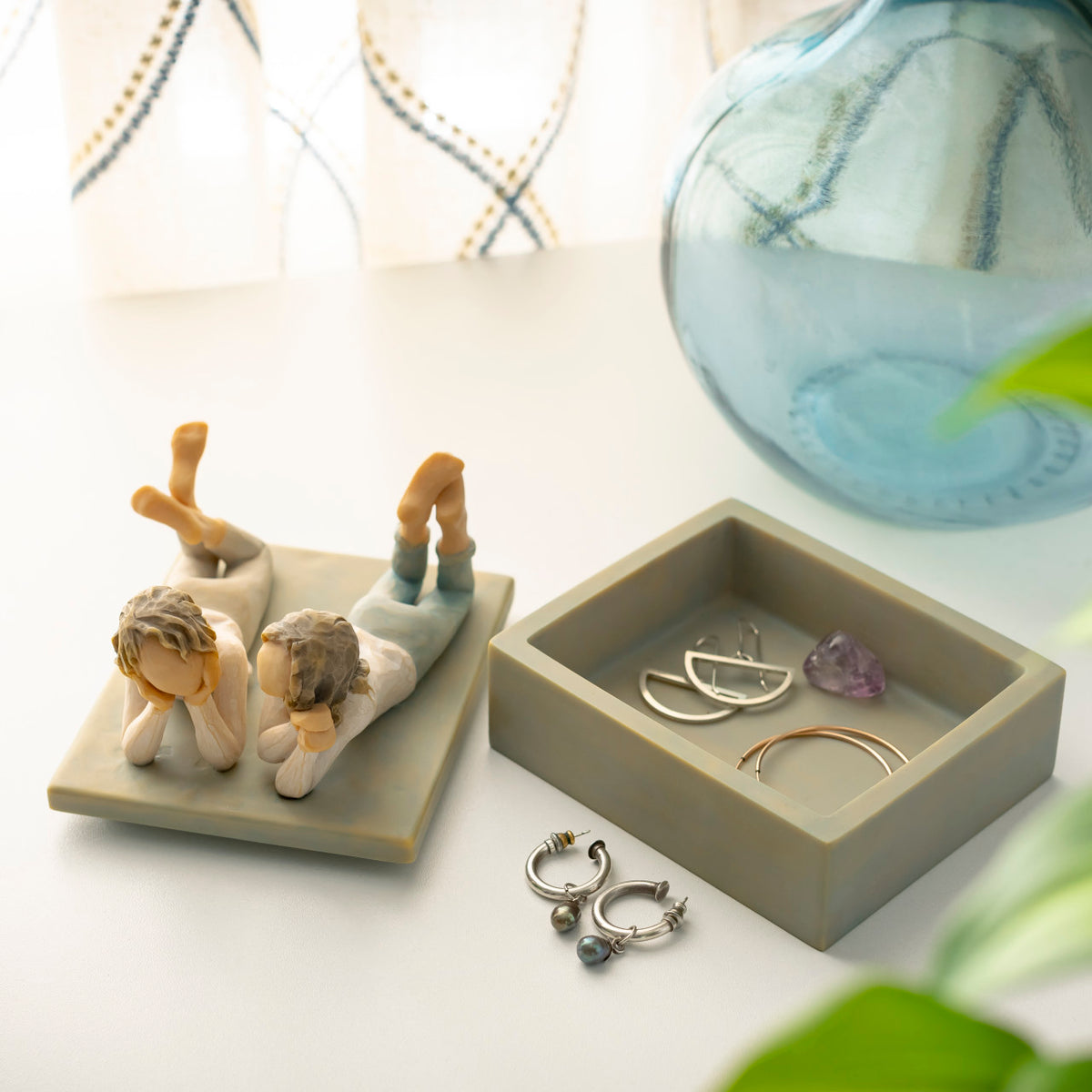Willow Tree Forever Friends Keepsake Box, 4.25”d x 3.5”w x 3.75”h hand-painted blue-gray rectangular resin box, sculpture of two girls lying next to each other affixed to lid, open with jewelry inside